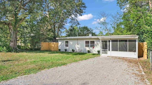 view of front of home with a sunroom and a front lawn