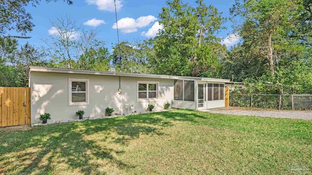 back of house featuring a lawn and a sunroom