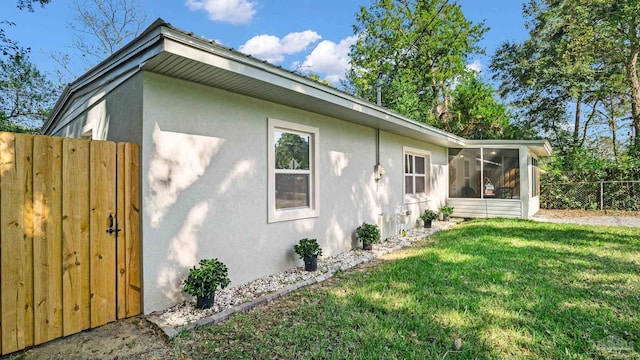 view of property exterior with a yard and a sunroom