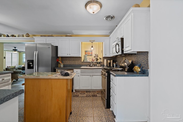 kitchen featuring visible vents, dark countertops, appliances with stainless steel finishes, a center island, and white cabinetry