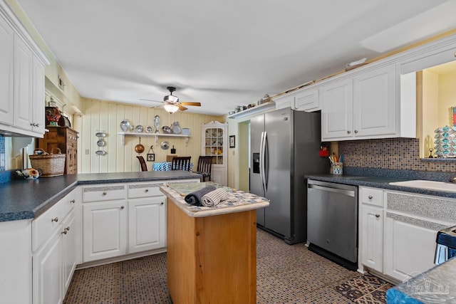 kitchen featuring appliances with stainless steel finishes, white cabinets, a peninsula, and light floors