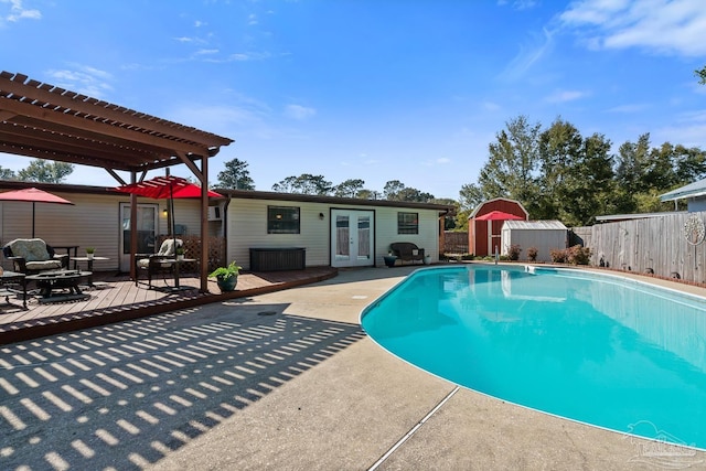 view of swimming pool with a fenced backyard, an outdoor structure, french doors, a pergola, and a storage unit