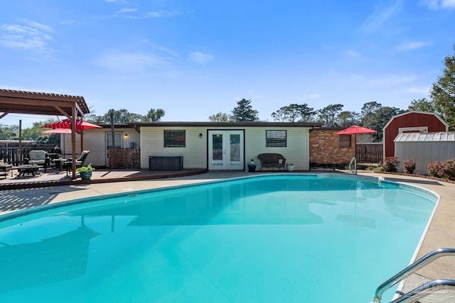 view of swimming pool featuring fence, an outbuilding, a fenced in pool, and french doors