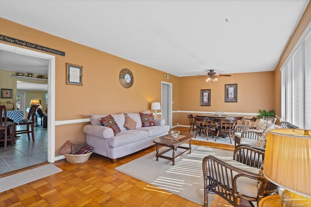 living area featuring baseboards and a ceiling fan