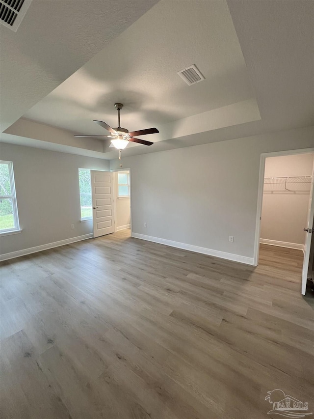 spare room featuring a tray ceiling, light hardwood / wood-style flooring, and ceiling fan