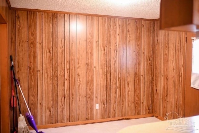 empty room with a textured ceiling and wooden walls