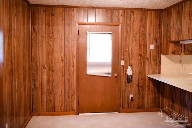 entryway with wooden walls and a textured ceiling