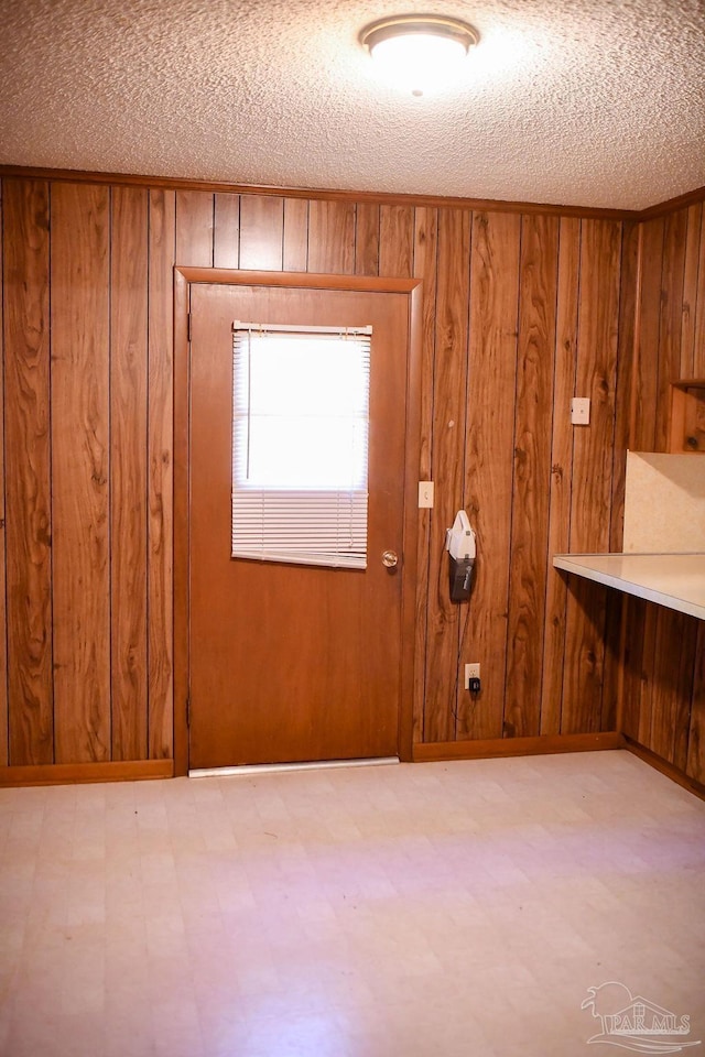 entryway featuring wood walls and a textured ceiling