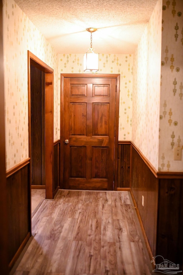 interior space featuring wooden walls, a textured ceiling, and hardwood / wood-style flooring