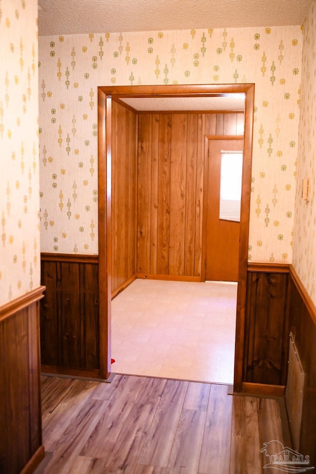 unfurnished room with wood walls and light wood-type flooring