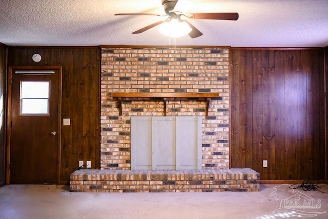 unfurnished living room with carpet flooring, wooden walls, ceiling fan, and a textured ceiling