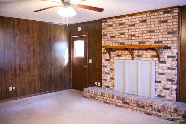 unfurnished living room featuring a textured ceiling, ceiling fan, crown molding, wooden walls, and carpet floors