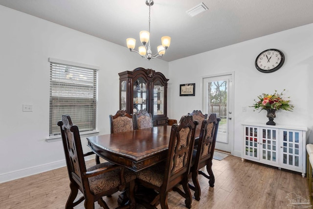 dining area with visible vents, baseboards, an inviting chandelier, and wood finished floors