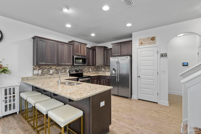 kitchen with visible vents, a sink, arched walkways, appliances with stainless steel finishes, and dark brown cabinets