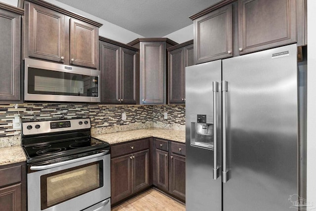 kitchen featuring decorative backsplash, light wood finished floors, dark brown cabinets, and appliances with stainless steel finishes