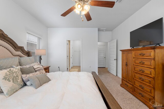 bedroom with a walk in closet, a ceiling fan, baseboards, and light carpet