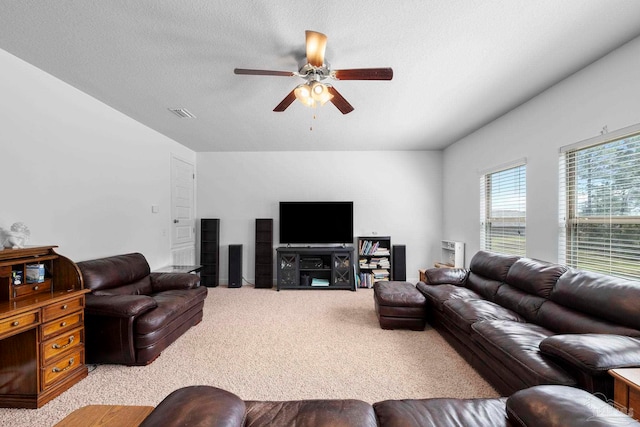 living area with visible vents, light colored carpet, a textured ceiling, and ceiling fan