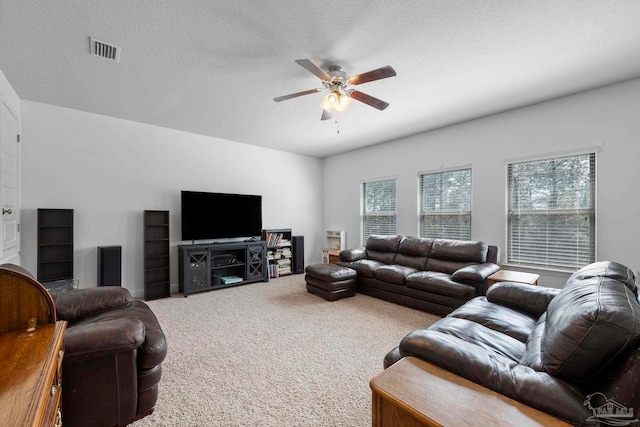 living room featuring visible vents, a textured ceiling, a ceiling fan, and carpet