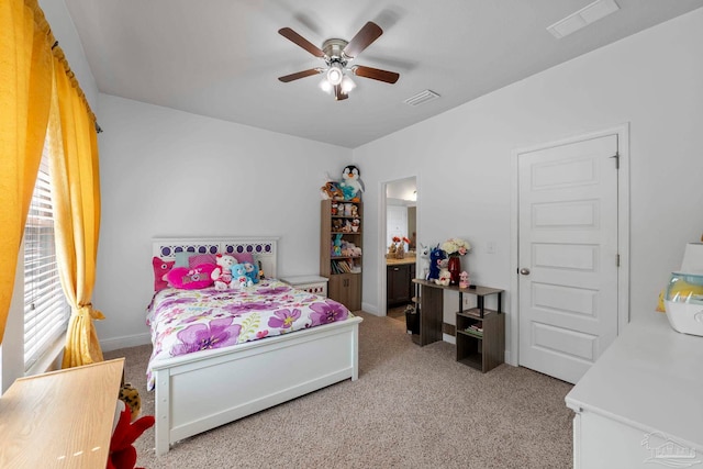 bedroom featuring ceiling fan, visible vents, light carpet, and ensuite bath