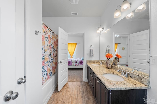 full bathroom with a sink, shower / tub combo with curtain, wood finished floors, and double vanity