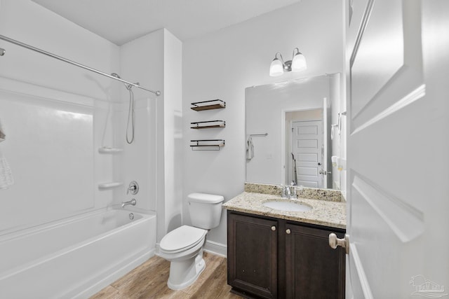 bathroom with vanity, wood finished floors, baseboards, shower / washtub combination, and toilet