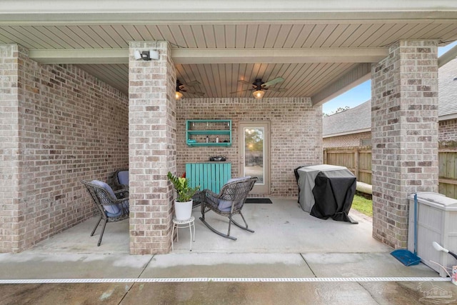 view of patio with area for grilling, a ceiling fan, and fence