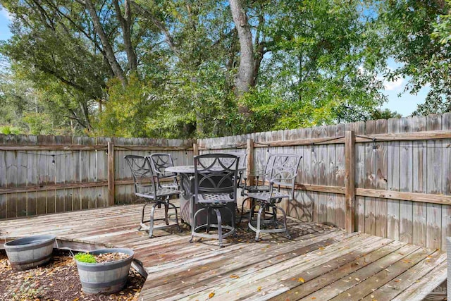 wooden terrace with outdoor dining area and a fenced backyard