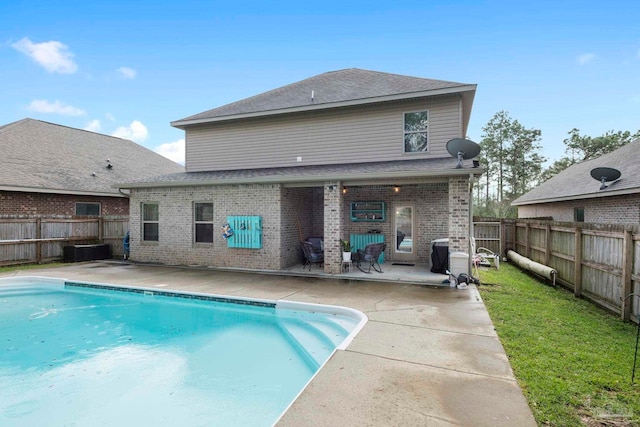 rear view of house with a fenced in pool, a fenced backyard, a lawn, a patio area, and brick siding