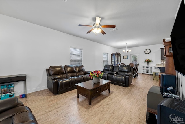 living area with light wood finished floors, ceiling fan with notable chandelier, and baseboards