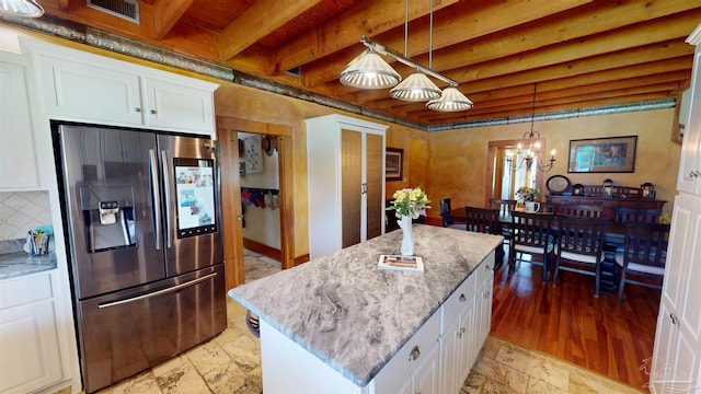 kitchen featuring beamed ceiling, pendant lighting, decorative backsplash, stainless steel refrigerator with ice dispenser, and a center island