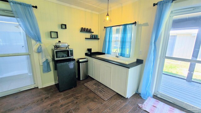 kitchen with ornamental molding, decorative light fixtures, dark hardwood / wood-style flooring, and refrigerator