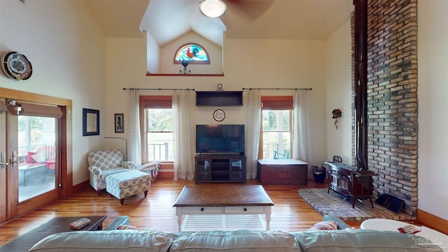 living room featuring high vaulted ceiling, wood-type flooring, and a wood stove