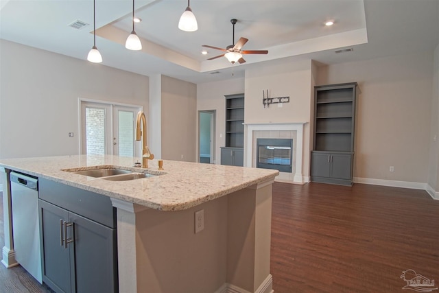 kitchen with a sink, dark wood-type flooring, visible vents, dishwasher, and a raised ceiling