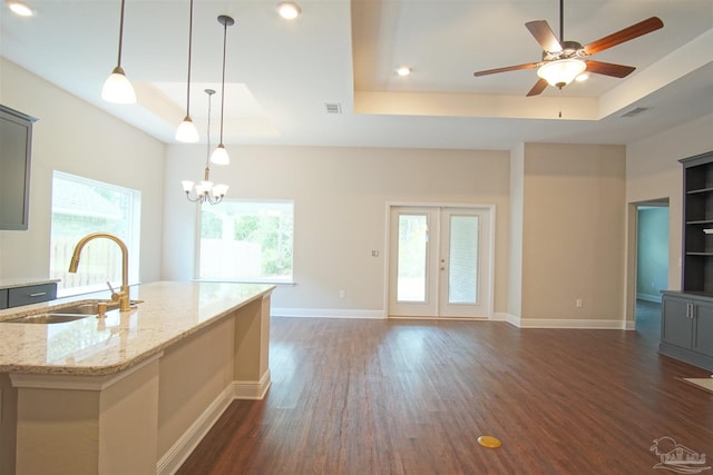 kitchen featuring a center island with sink, dark wood finished floors, a raised ceiling, and a sink