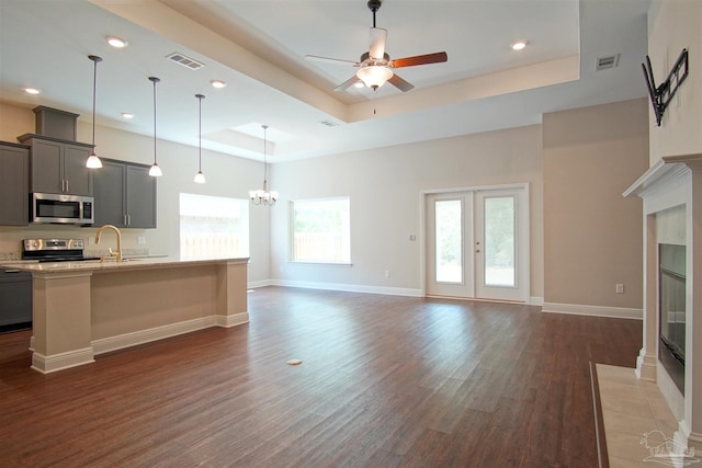 living area featuring plenty of natural light, a tiled fireplace, wood finished floors, and a raised ceiling