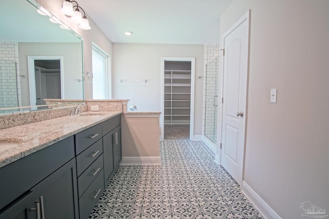 bathroom featuring a sink, baseboards, a shower with door, a walk in closet, and double vanity