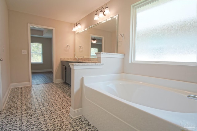 full bath featuring baseboards, a garden tub, and vanity
