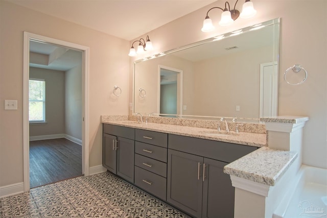 full bath featuring double vanity, visible vents, baseboards, and a sink