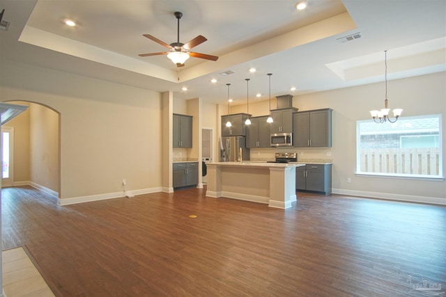 kitchen featuring a raised ceiling, stainless steel appliances, open floor plan, and gray cabinetry