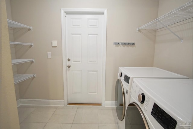 laundry room with washing machine and clothes dryer, light tile patterned floors, baseboards, and laundry area