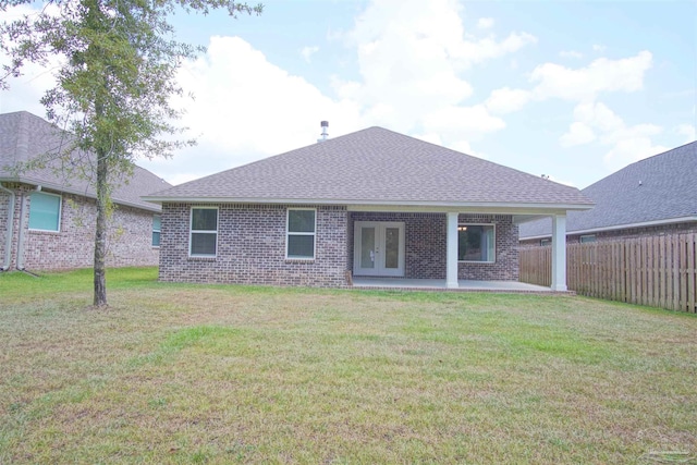 rear view of property with a yard, french doors, brick siding, fence, and roof with shingles