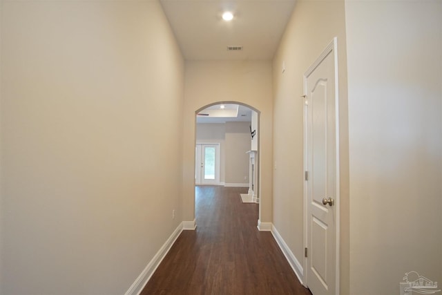 hall with baseboards, arched walkways, dark wood-style floors, and visible vents