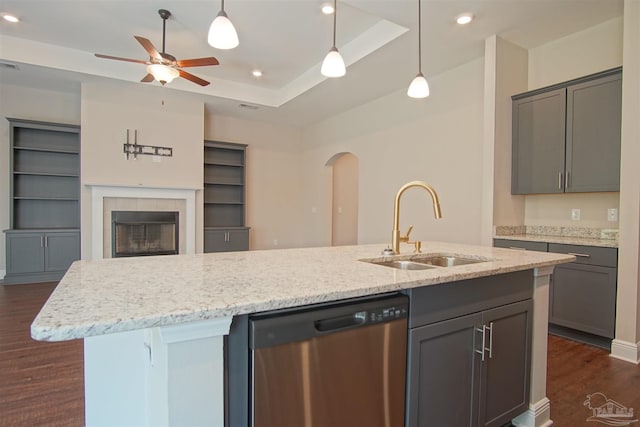 kitchen featuring stainless steel dishwasher, dark wood finished floors, a sink, open floor plan, and arched walkways