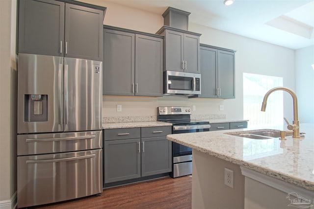 kitchen with a sink, dark wood-style flooring, light stone countertops, gray cabinetry, and appliances with stainless steel finishes