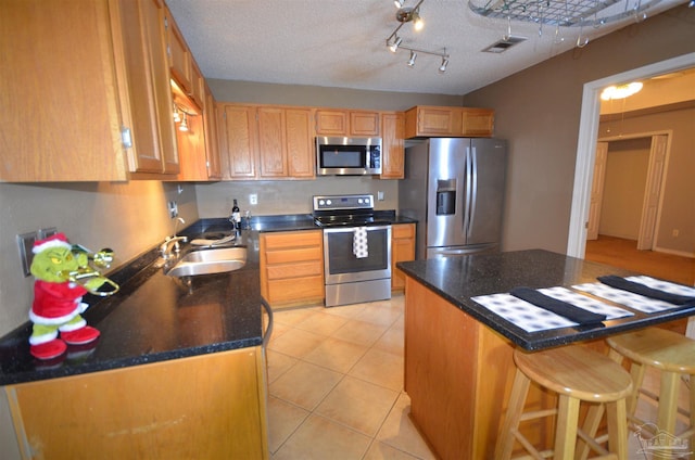 kitchen featuring visible vents, a breakfast bar area, a sink, appliances with stainless steel finishes, and light tile patterned floors