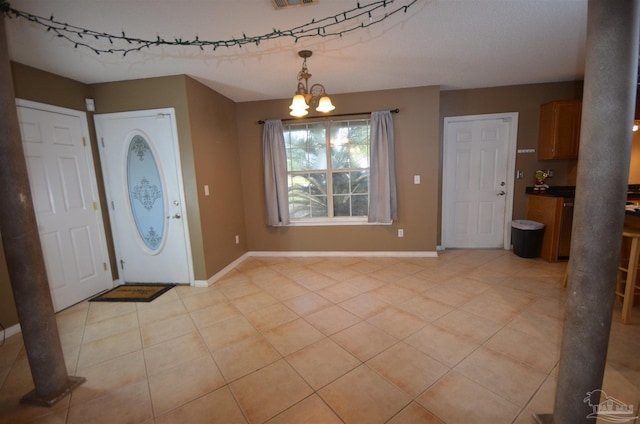 foyer with light tile patterned floors, baseboards, visible vents, and a notable chandelier