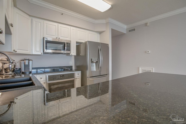 kitchen with appliances with stainless steel finishes, crown molding, sink, dark stone countertops, and white cabinetry