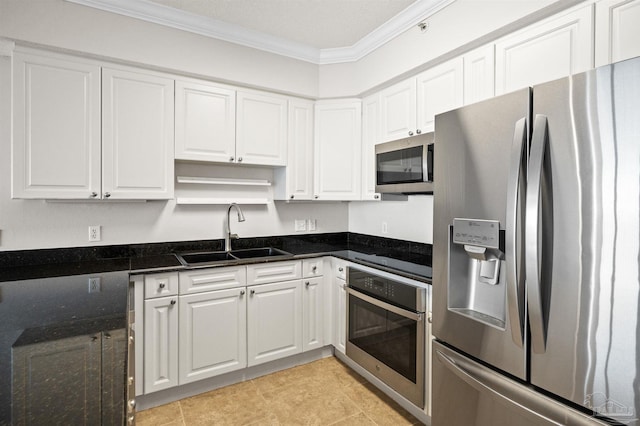 kitchen with white cabinetry, sink, stainless steel appliances, dark stone counters, and ornamental molding