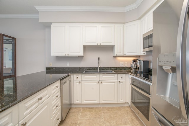 kitchen with appliances with stainless steel finishes, dark stone counters, crown molding, sink, and white cabinetry