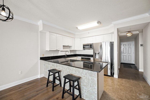 kitchen with pendant lighting, sink, a textured ceiling, appliances with stainless steel finishes, and white cabinetry